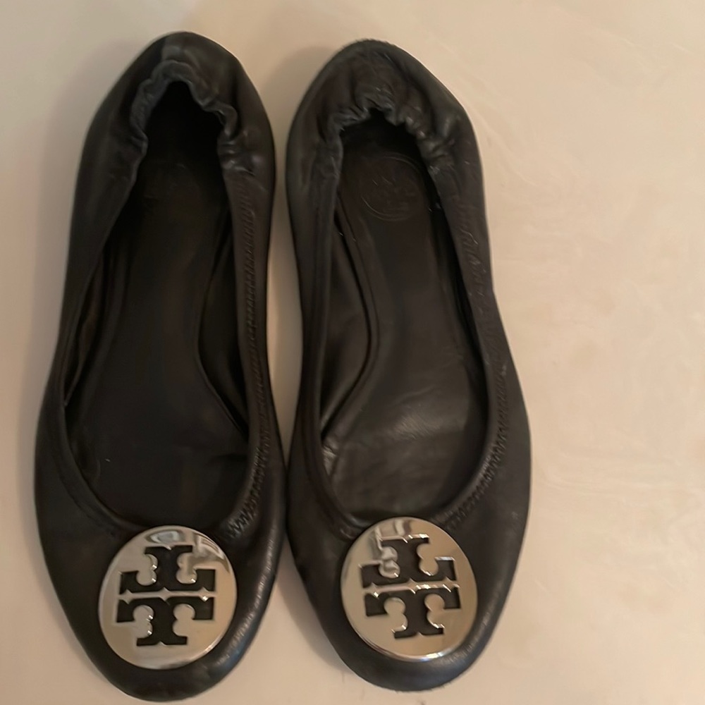 Tory Burch black flats with silver emblem.